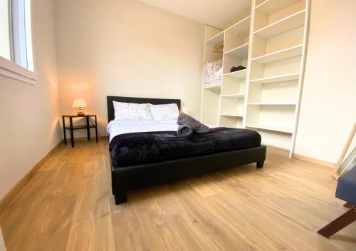 普瓦捷Aux Pommiers - Poitiers CHU - CAMPUS - La Conciergerie的一间卧室配有一张带黑色搁脚凳的床
