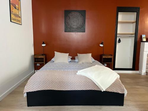 拉沙里泰L’Etape, cœur de ville的一间卧室配有一张带橙色墙壁的大床