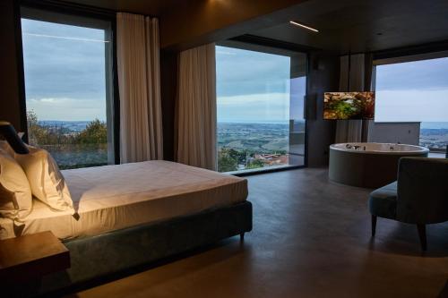 SaludecioLe Agavi Resort & SPA的卧室设有1张床、1个浴缸和1个大窗户
