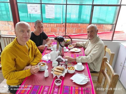 库斯科Welcome Cusco Hostel的一群坐在餐桌上吃食物的男人