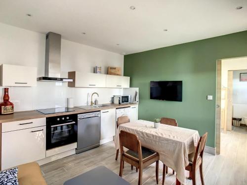 维特罗勒Appartement aux salins du lion的一间带桌椅的厨房和一间带绿色墙壁的厨房