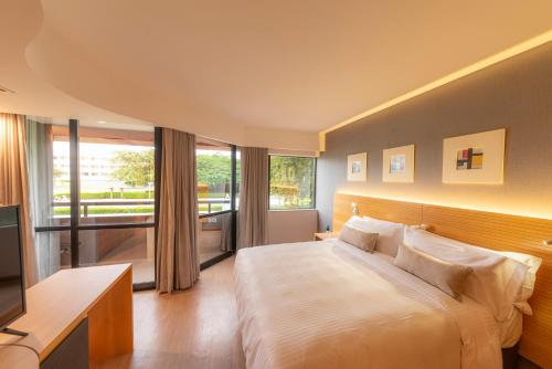 巴西利亚金色郁金香巴西利亚阿尔沃拉达酒店的一间卧室设有一张大床和一个大窗户