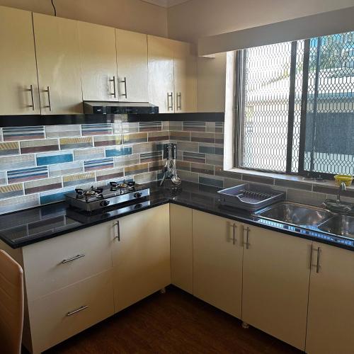 南迪KumarVacation Home 38 Kennedy Road Unit 1的厨房配有白色橱柜、水槽和窗户。