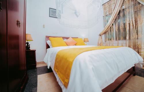 布琼布拉城市山丘酒店的一间卧室配有一张黄色和白色床单