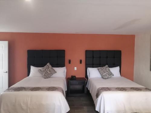 SabinasHotel Express Inn的橙色墙壁客房的两张床