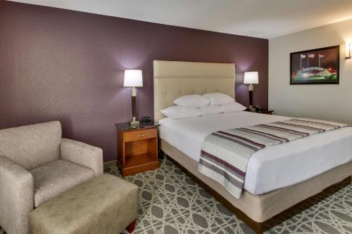 波普勒布拉夫Drury Inn & Suites Poplar Bluff的配有一张床和一把椅子的酒店客房