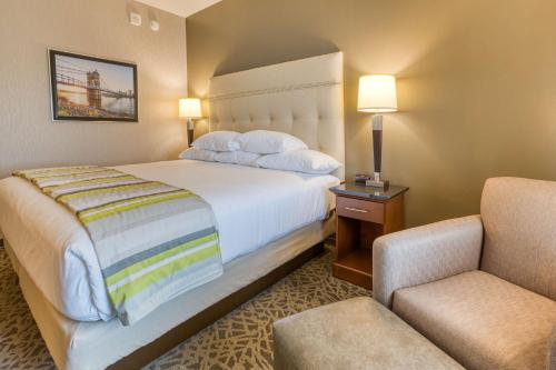梅森Drury Inn & Suites Cincinnati Northeast Mason的配有一张床和一把椅子的酒店客房
