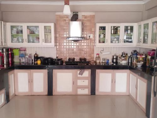 大吉岭Pinewood Homestay的厨房配有白色橱柜和黑色台面