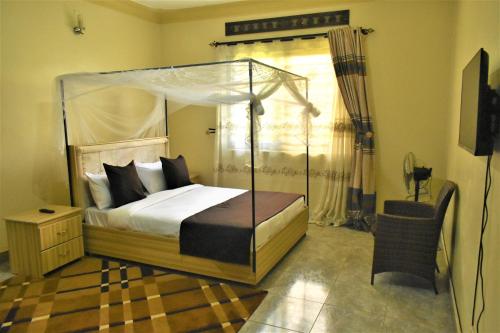 坎帕拉Beautiful home opposite Speke Resort Munyonyo near Lake Victoria的一间卧室配有一张天蓬床和一把椅子