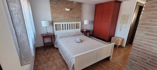 阿达莱斯Apartamentos luna的卧室配有白色床、两张桌子和砖墙