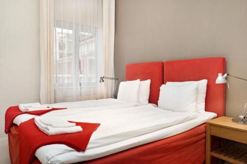 赫尔辛堡Stadsparken Apartments的窗户客房内的一张红白色的床