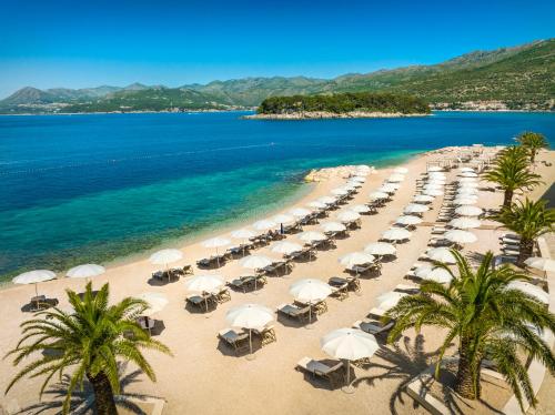 杜布罗夫尼克Valamar Lacroma Dubrovnik Hotel的海滩上放着一把遮阳伞,大海