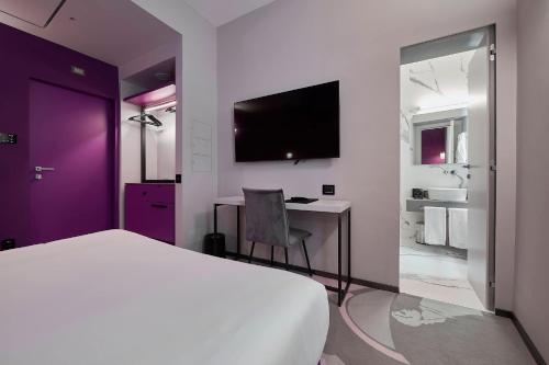 罗马MyTALE Creative Academy Hotel的一间卧室配有一张床和一张书桌及电视