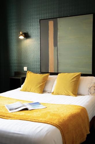 瑞卢维尔莱潘Hôtel des Pins的一张带黄色枕头的大床和上面的书