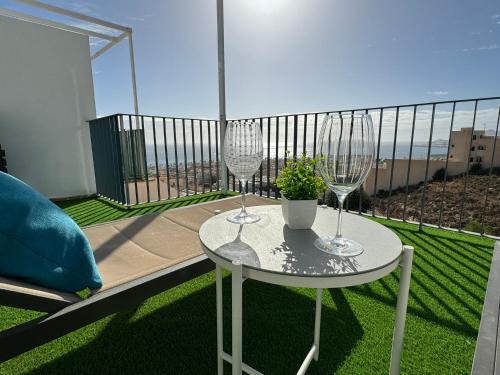 卡沃内拉斯Apartamento Cervantes con terraza y vistas al mar的阳台上配有带2个酒杯的白色桌子