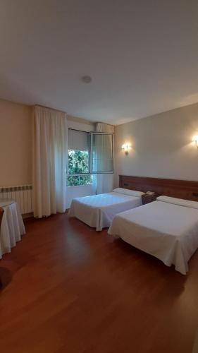 莱昂Hotel Las Moreras的酒店客房设有两张床和窗户。