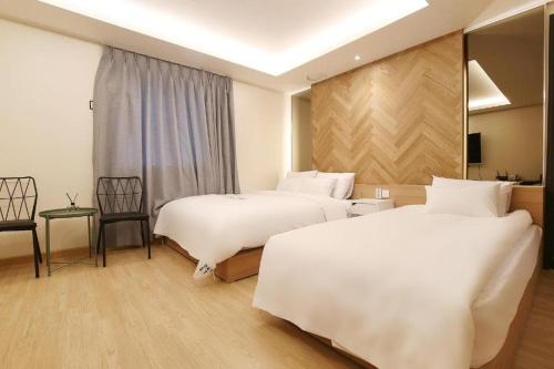 天安市Urban Stay的酒店客房带两张床和一张桌子以及椅子。