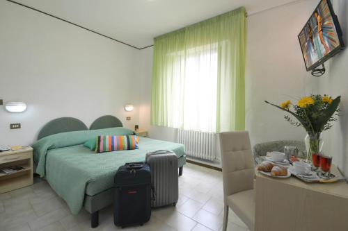 基安奇安诺泰尔梅马提尼酒店的一间卧室配有一张床和一张带行李箱的桌子