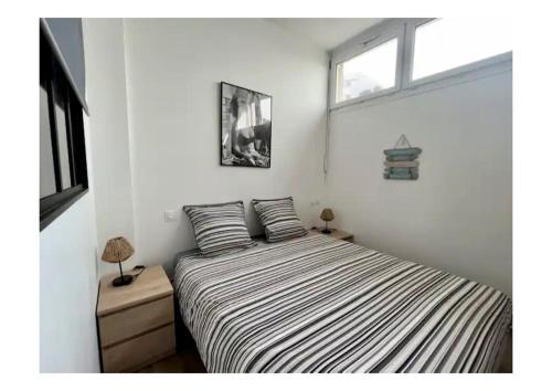 勒阿弗尔Appartement Louise的一间卧室配有一张带条纹床单的床和窗户。