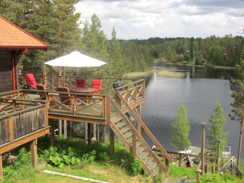 赖特维克Holiday Home Nedre Gärdsjö - DAN086 by Interhome的湖畔甲板上配有椅子和遮阳伞
