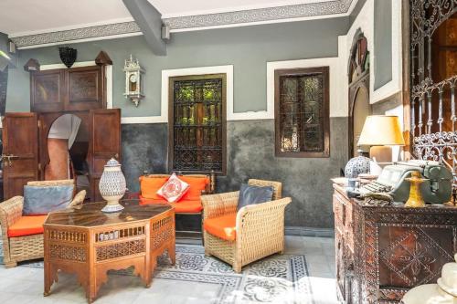 马拉喀什Riad des Mile Nuits的客厅配有橙色椅子和桌子