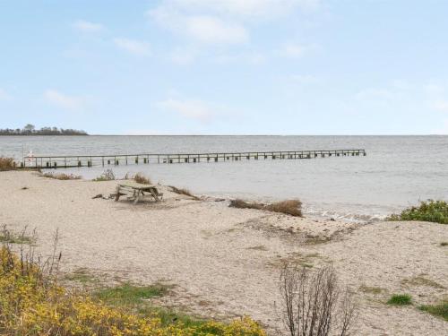 阿森斯Holiday Home Maybrit - 50m from the sea in Funen by Interhome的海滩上的长凳,在水中设有一个码头