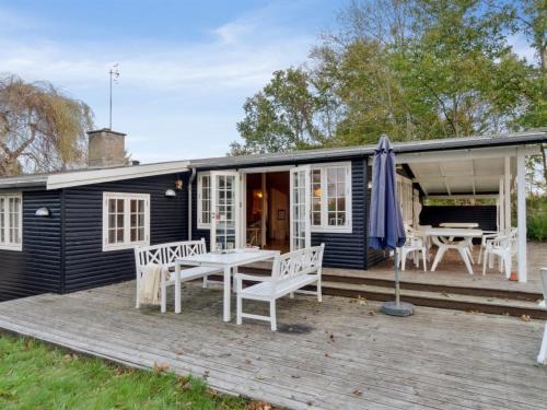 齐斯维勒莱厄Holiday Home Rami - 2km from the sea in Sealand by Interhome的黑色小屋,在甲板上配有桌椅
