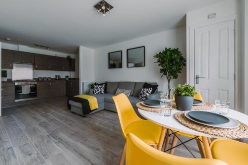 格拉斯哥SuperbSleep Apartments的厨房以及带桌子和黄色椅子的客厅。