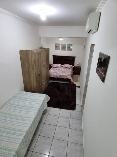 卡拉瓜塔图巴Kitnets em Caraguatatuba的一间带两张床的卧室和一台电视