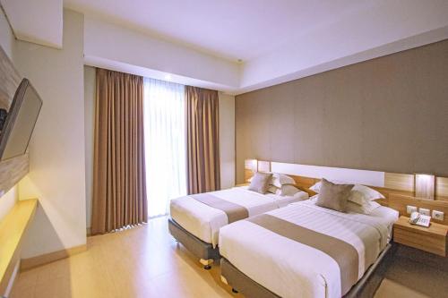 日惹Hotel FortunaGrande Seturan Yogyakarta的酒店客房设有两张床和窗户。