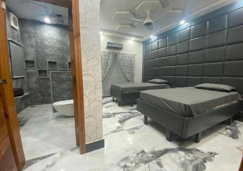 拉合尔The Bahria Town Hotel & Suites的一间带两张床的卧室和一间带浴缸的浴室