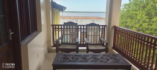 拉穆New Mahrus Hotel Lamu的阳台配有两把椅子,享有海景。