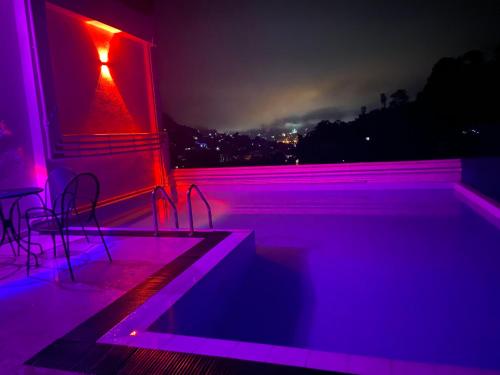 康提Aurelia inn的一个带椅子和紫色灯的游泳池的房间