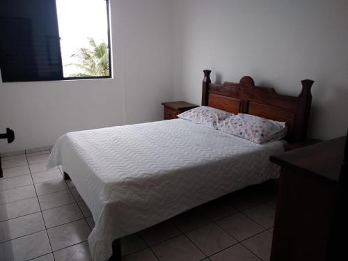 蒙加瓜WI-FI 600MEGA 8 pessoas CENTRO da cidade frente mar 3quartos 2 carros的卧室配有白色的床和木制床头板