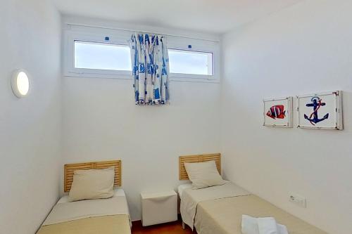 比尼贝卡Apartamento Binibeca Nou Cami de Cavalls的带2扇窗户的客房内的2张床