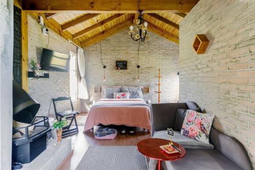 兰舒凯马杜O Chalé Encantado - Rancho Queimado的卧室配有床和沙发,位于砖墙内