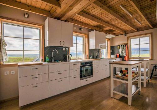 SkogarFagrafell Hostel的厨房配有白色橱柜、桌子和窗户。