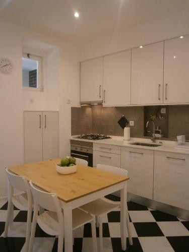 里斯本明星公寓的厨房配有木桌和白色橱柜。
