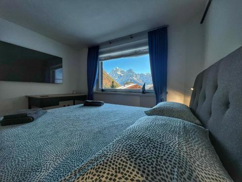 摩德纳迪-坎皮格里奥Bonapace Dolomites Apartments的一间卧室设有一张大床和大窗户