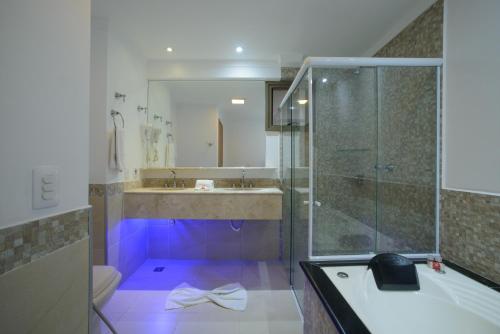 阿蒂巴亚Faro Hotel Atibaia的浴室配有浴缸和紫色照明淋浴。
