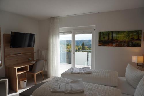 多贝尔Hotel Talblick的一间带两张床、一台电视和一个阳台的卧室