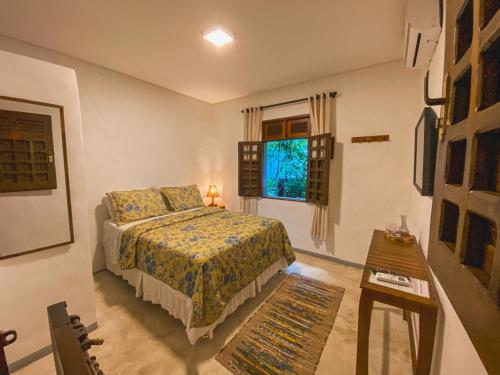 佩德拉斯港Maruê Guesthouse Porto de Pedras的一间卧室配有一张床、一张桌子和一个窗户。