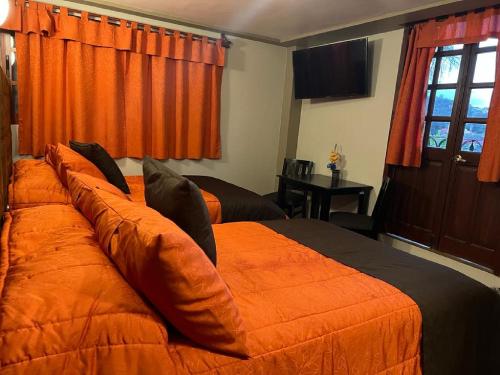 米内拉尔德尔蒙特Hotel Paraiso Real Plus的一间卧室设有两张带橙色床单的床和窗户。