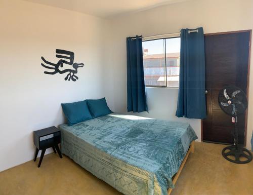 洛维托斯Tayta Surf House的一间卧室配有一张床和一个带风扇的窗户。