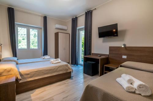 拉默齐亚泰尔默Hotel Ristorante La Mimosa的酒店客房设有两张床和一台平面电视。