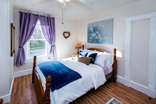 HartfordVintage downtown flat near Holy Hill, Golf &Ski的一间卧室配有一张大床和紫色窗帘