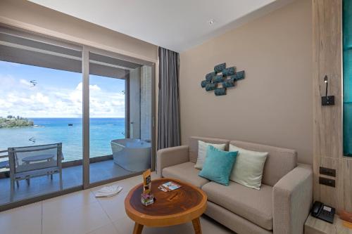 卡马拉海滩Cape Sienna Phuket Gourmet Hotel & Villas - SHA Extra Plus的带沙发的客厅,享有海景