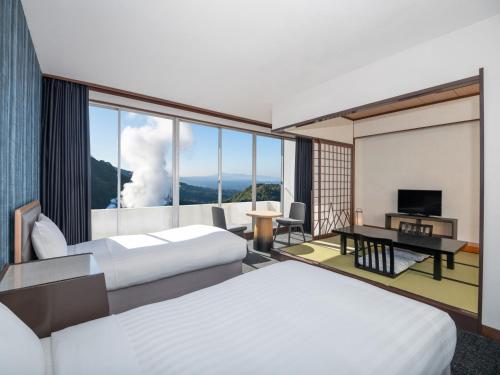 雾岛市雾岛国际大酒店的酒店客房设有两张床、一张桌子和一台电视。