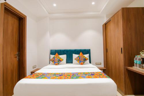 新德里FabHotel La Serene BnB的卧室配有一张带彩色枕头的大型白色床。