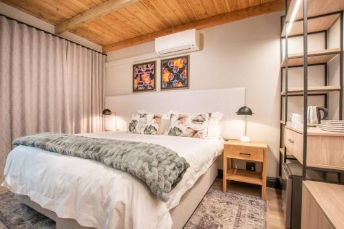 布历根非尔Eikenhof Estate的卧室设有白色的床和木制天花板。